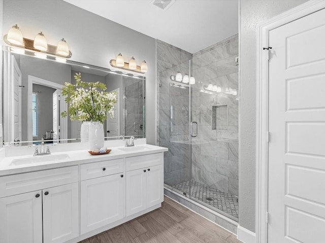 bathroom featuring vanity, a shower with shower door, and wood-type flooring