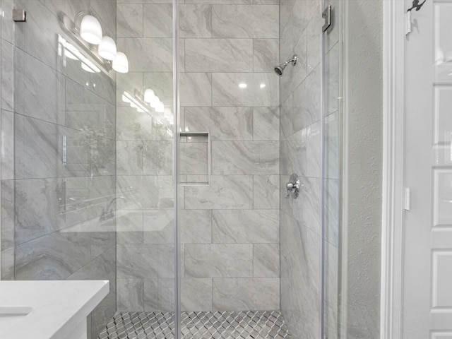 bathroom featuring a shower with door and vanity