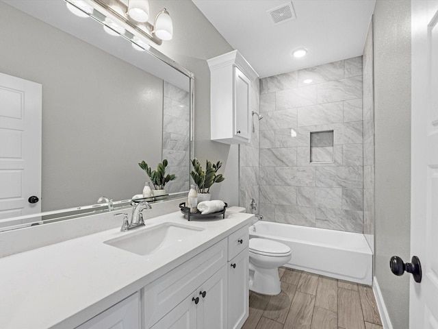 full bathroom with tiled shower / bath combo, vanity, and toilet