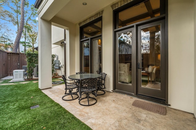 entrance to property featuring a yard, a patio area, and french doors