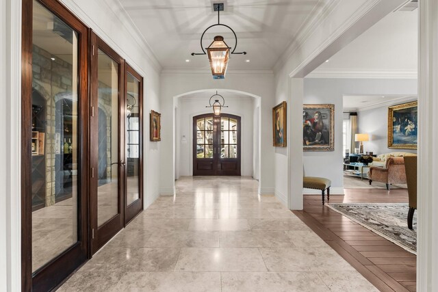 foyer featuring french doors, crown molding, and an inviting chandelier