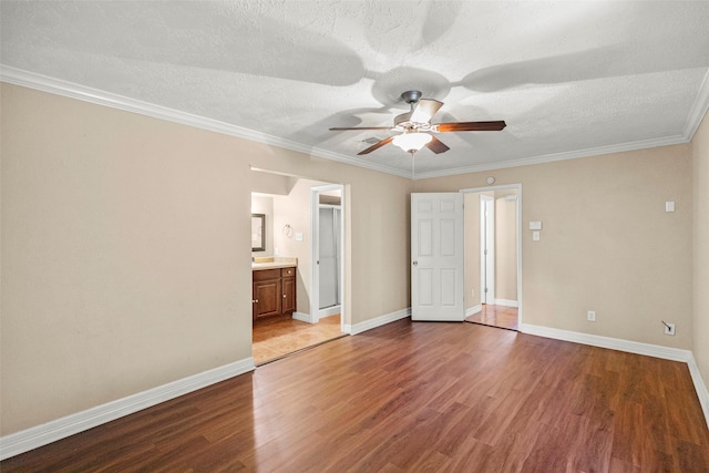 unfurnished bedroom featuring ensuite bath, hardwood / wood-style flooring, ornamental molding, ceiling fan, and a textured ceiling