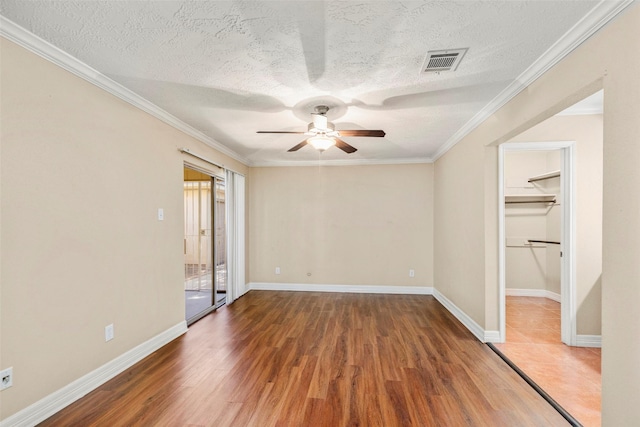 unfurnished bedroom with dark hardwood / wood-style floors, ornamental molding, a spacious closet, ceiling fan, and a textured ceiling