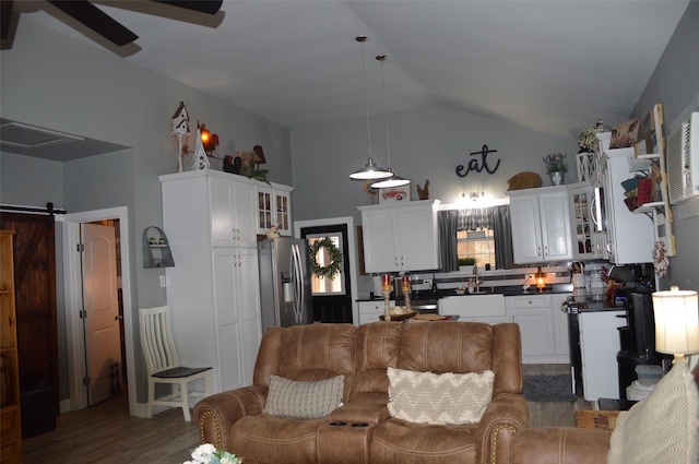 living room with sink, vaulted ceiling, ceiling fan, a barn door, and hardwood / wood-style floors