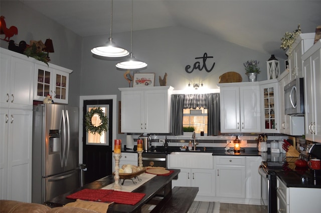 kitchen featuring lofted ceiling, white cabinetry, hanging light fixtures, stainless steel appliances, and backsplash