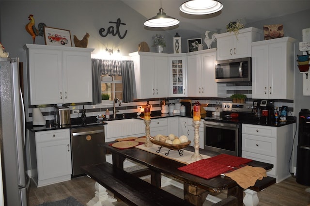 kitchen with lofted ceiling, decorative backsplash, white cabinets, and appliances with stainless steel finishes