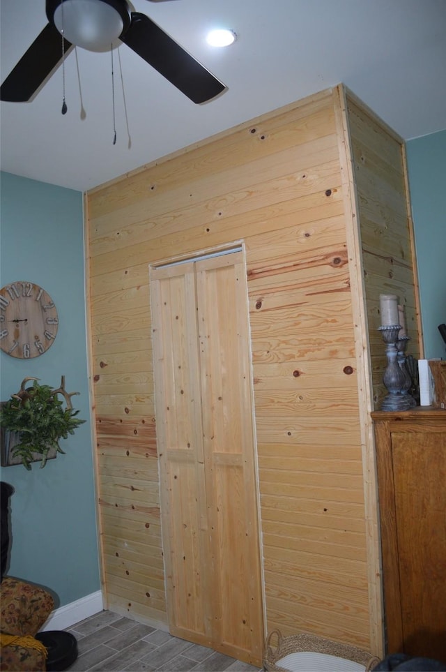 interior space with ceiling fan and wood walls