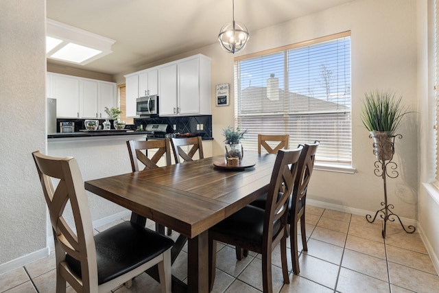 tiled dining space featuring a healthy amount of sunlight and an inviting chandelier