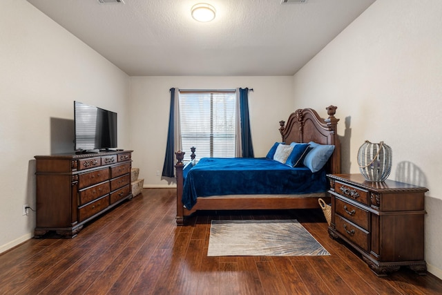 bedroom with dark hardwood / wood-style floors and a textured ceiling