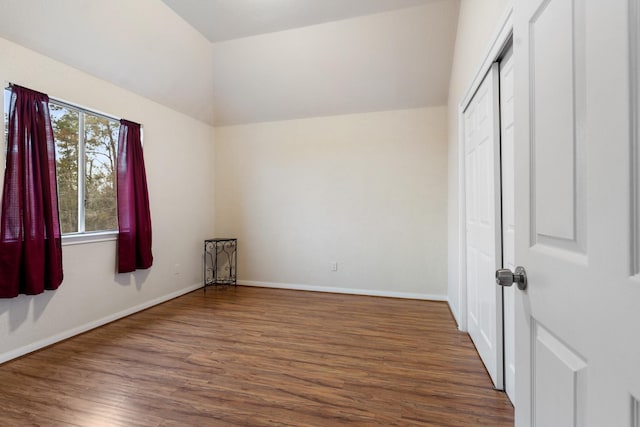 unfurnished bedroom with dark wood-type flooring, a closet, and vaulted ceiling