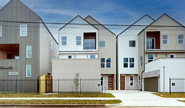 multi unit property featuring board and batten siding, concrete driveway, an attached garage, and fence