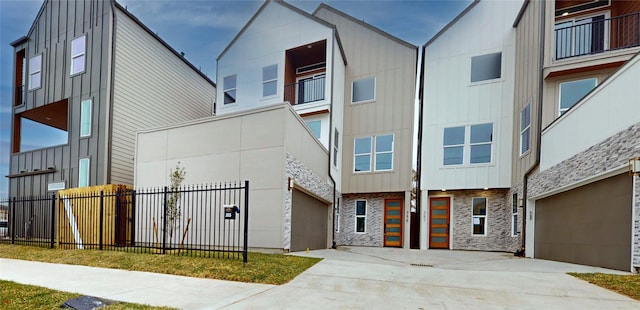 exterior space featuring stone siding, board and batten siding, driveway, and fence