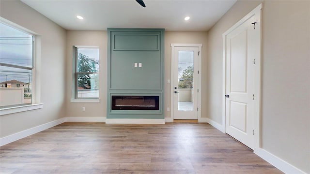 unfurnished living room featuring a wealth of natural light, a fireplace, and light wood-type flooring