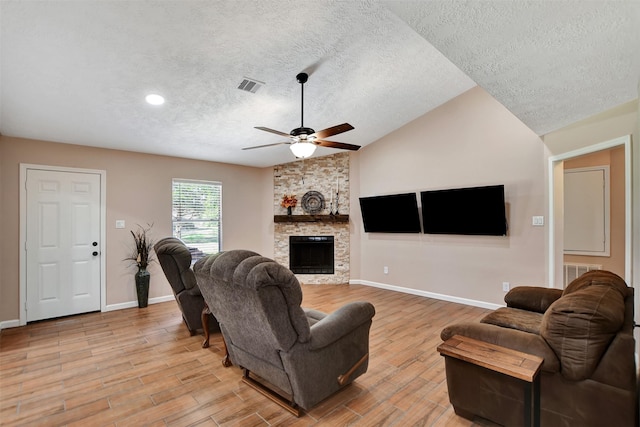 living room with ceiling fan, a fireplace, a textured ceiling, and vaulted ceiling