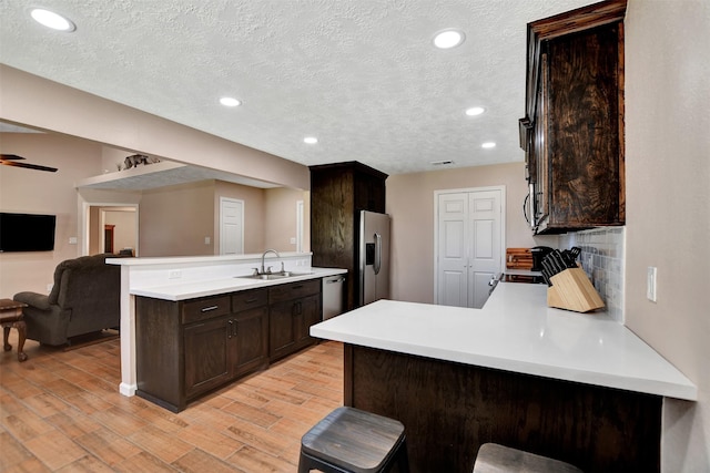 kitchen featuring sink, backsplash, a kitchen breakfast bar, kitchen peninsula, and stainless steel appliances