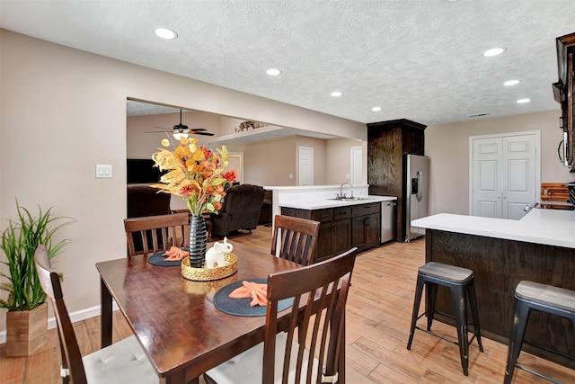 dining room with ceiling fan, sink, a textured ceiling, and light hardwood / wood-style flooring