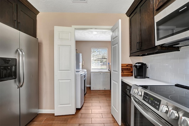 kitchen with stainless steel appliances, separate washer and dryer, dark brown cabinets, and a textured ceiling