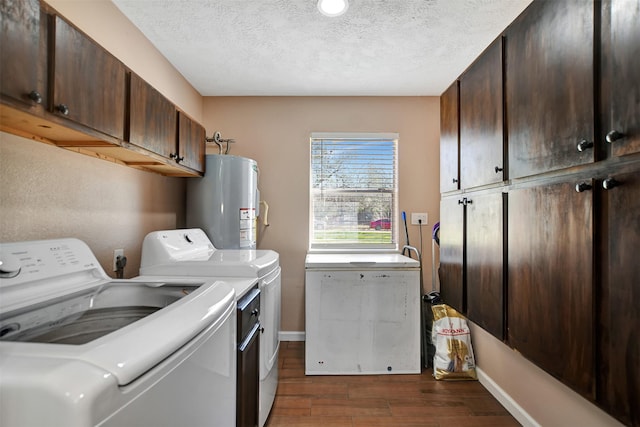 clothes washing area featuring dark hardwood / wood-style floors, water heater, cabinets, washing machine and dryer, and a textured ceiling