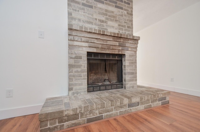 interior details with a brick fireplace and wood-type flooring