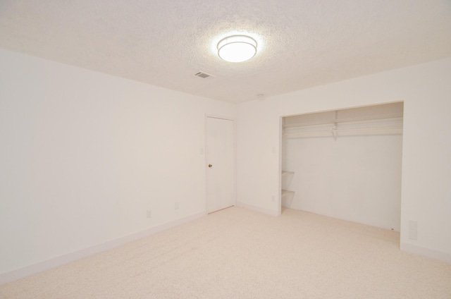 unfurnished bedroom with carpet, a textured ceiling, and a closet