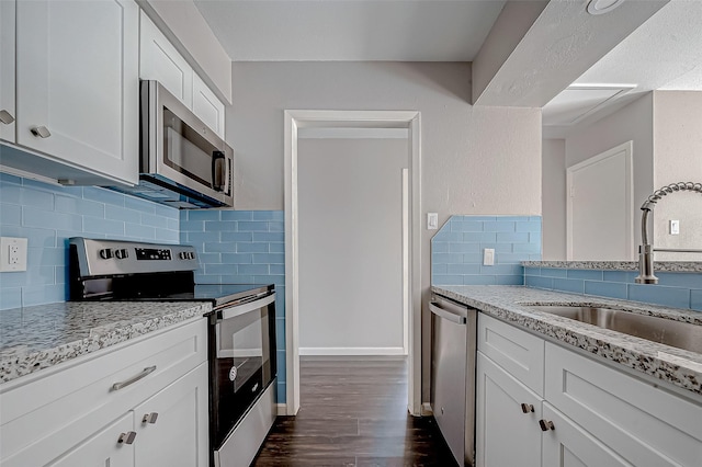 kitchen with white cabinetry, sink, decorative backsplash, light stone counters, and stainless steel appliances