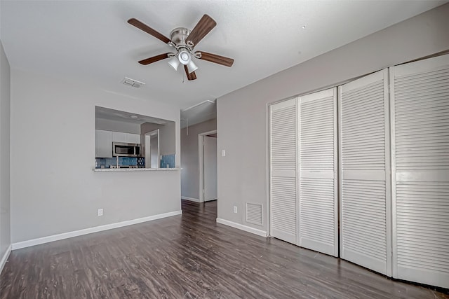 unfurnished living room featuring dark hardwood / wood-style flooring and ceiling fan