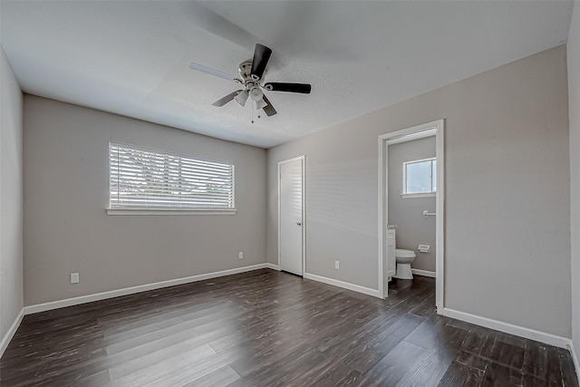 unfurnished bedroom featuring connected bathroom, dark wood-type flooring, a closet, and ceiling fan