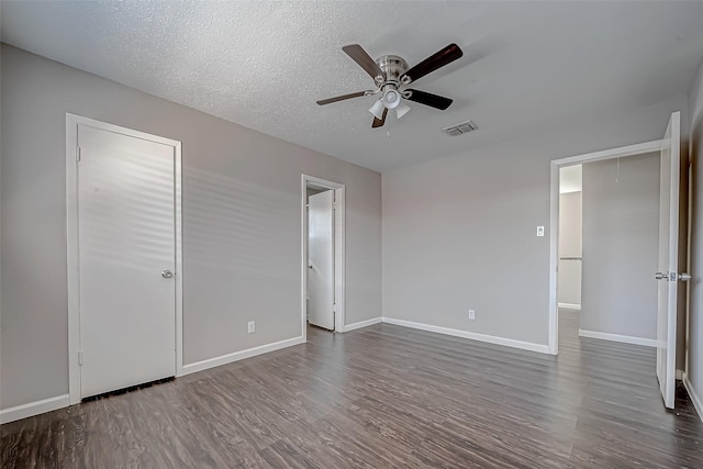 unfurnished bedroom featuring dark wood-type flooring, a textured ceiling, and ceiling fan