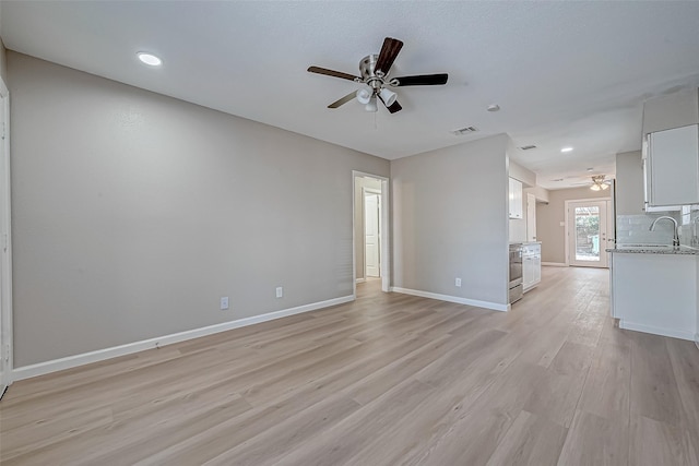 unfurnished living room with ceiling fan and light wood-type flooring