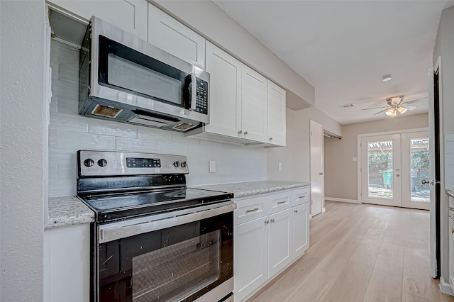 kitchen with appliances with stainless steel finishes, light stone counters, white cabinets, french doors, and light wood-type flooring