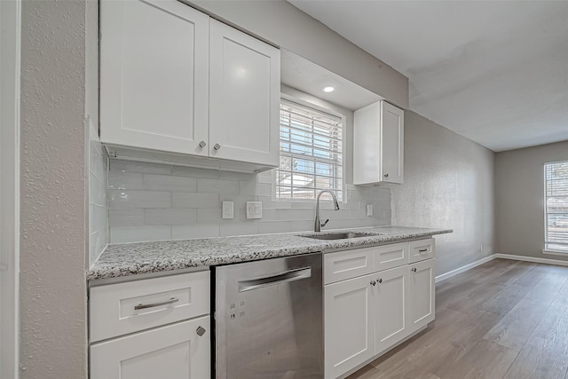 kitchen featuring tasteful backsplash, white cabinetry, sink, and stainless steel dishwasher