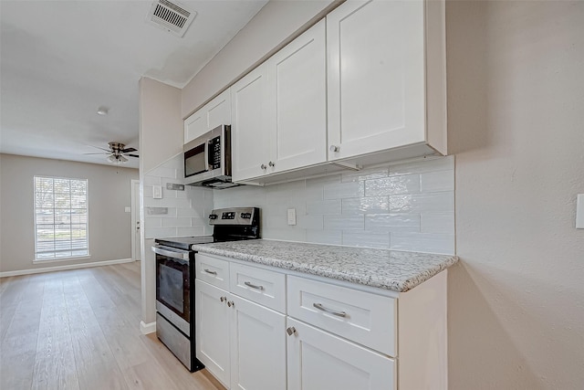 kitchen featuring white cabinetry, stainless steel appliances, light stone counters, light hardwood / wood-style floors, and decorative backsplash