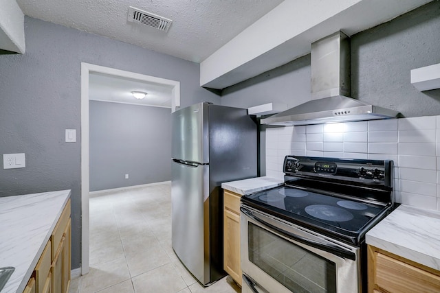 kitchen featuring wall chimney exhaust hood, a textured ceiling, light tile patterned floors, appliances with stainless steel finishes, and backsplash