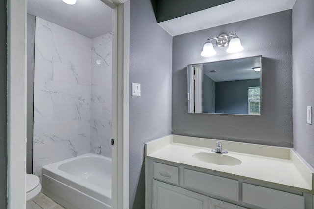 full bathroom featuring vanity, tiled shower / bath combo, tile patterned floors, and toilet