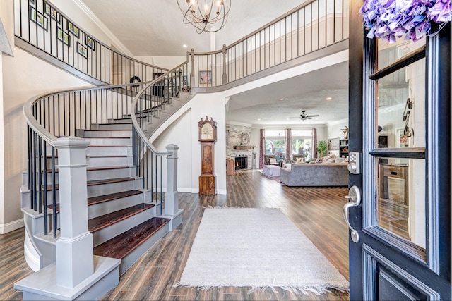 foyer entrance featuring ornamental molding, dark hardwood / wood-style floors, ceiling fan with notable chandelier, and a towering ceiling