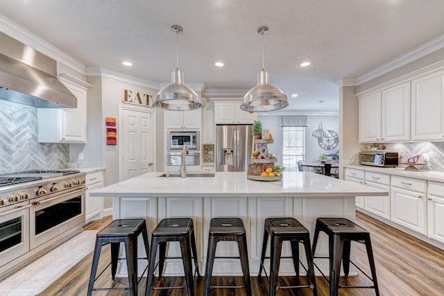 kitchen with stainless steel appliances, an island with sink, and white cabinetry