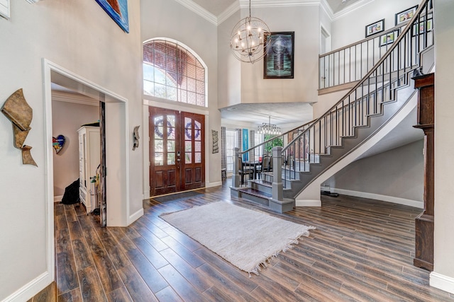 foyer entrance featuring dark wood-type flooring, ornamental molding, a chandelier, and a high ceiling