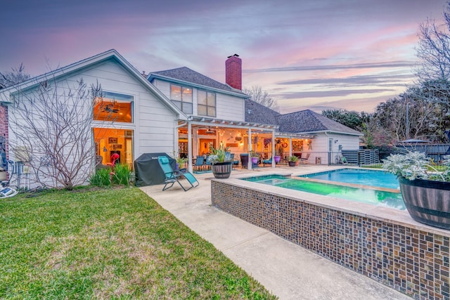 back house at dusk with a yard, a pergola, and a patio area