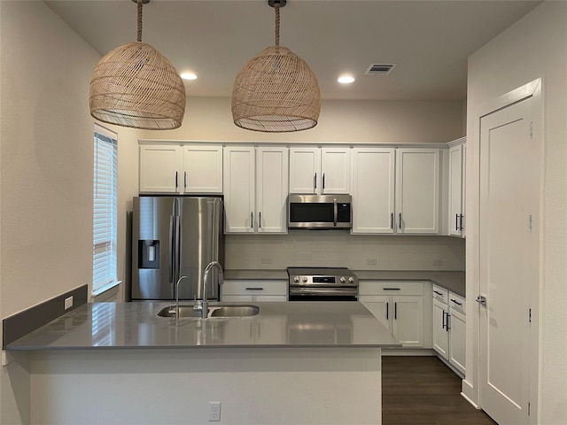 kitchen with sink, white cabinetry, stainless steel appliances, decorative backsplash, and decorative light fixtures