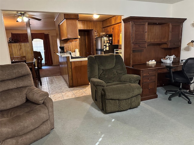 carpeted living room featuring ceiling fan and wood walls