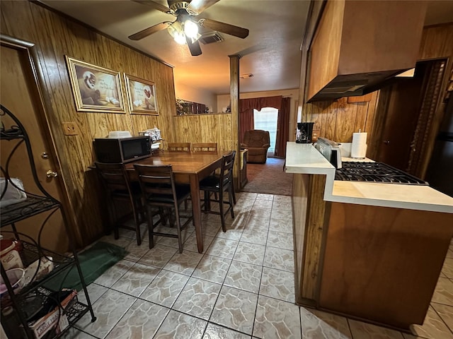 dining space featuring decorative columns, ceiling fan, and wood walls