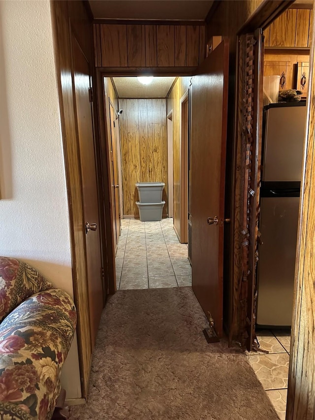 corridor featuring light carpet and wooden walls