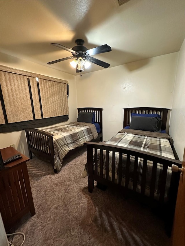 bedroom with ceiling fan and dark colored carpet