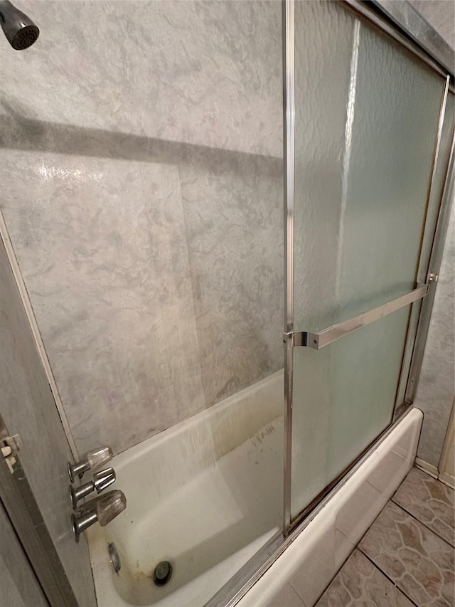 bathroom with tile patterned flooring and shower / bath combination with glass door