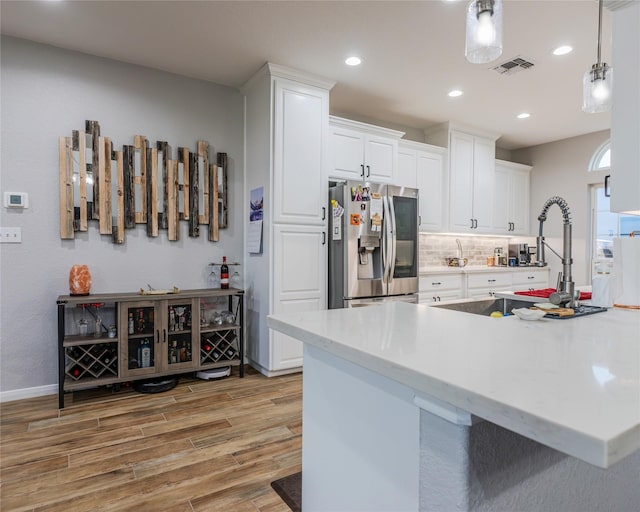 kitchen with white cabinetry, stainless steel fridge, kitchen peninsula, and light wood-type flooring