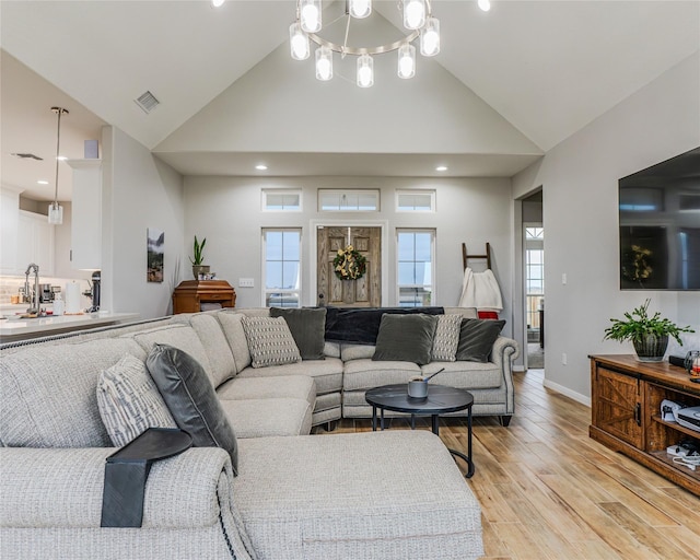 living room featuring high vaulted ceiling and light hardwood / wood-style flooring