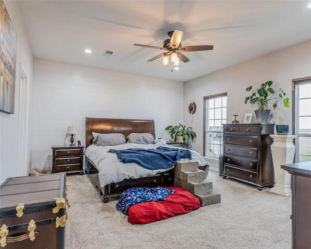 bedroom featuring ceiling fan, light carpet, and multiple windows