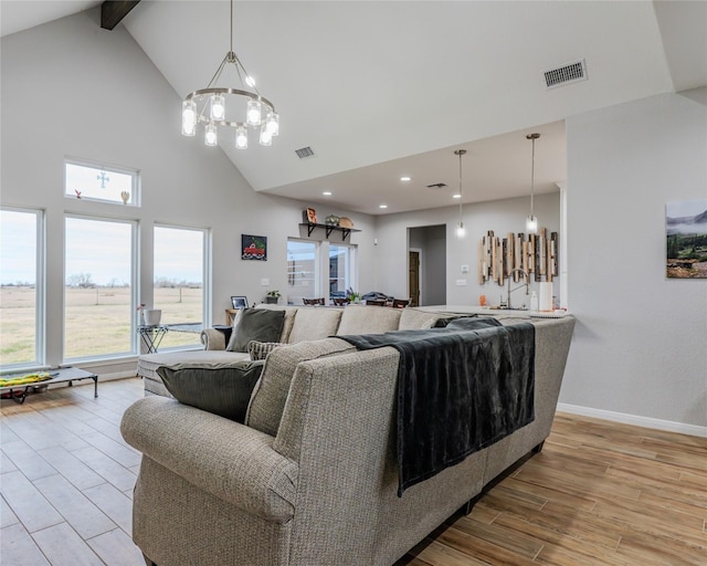 living room with beam ceiling, high vaulted ceiling, a notable chandelier, and light wood-type flooring