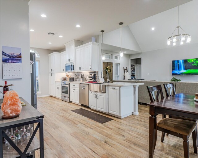 kitchen featuring white cabinetry, sink, decorative light fixtures, and appliances with stainless steel finishes