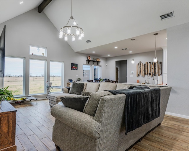 living room featuring a notable chandelier, beam ceiling, wood-type flooring, and high vaulted ceiling